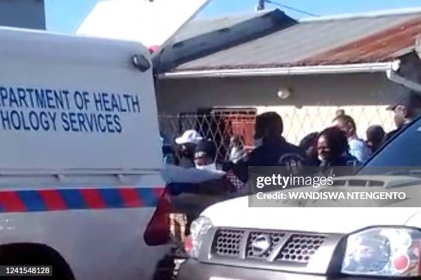 In this videograb taken from an AFP reporter, emergency services personnel load a body into a pathology services truck at a township pub in South...