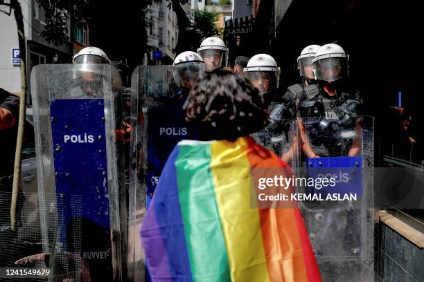 Participant faces riot policemen wearing a rainbow flag during a Pride march in Istanbul, on June 26, 2022. Turkish police forcibly intervened in a...