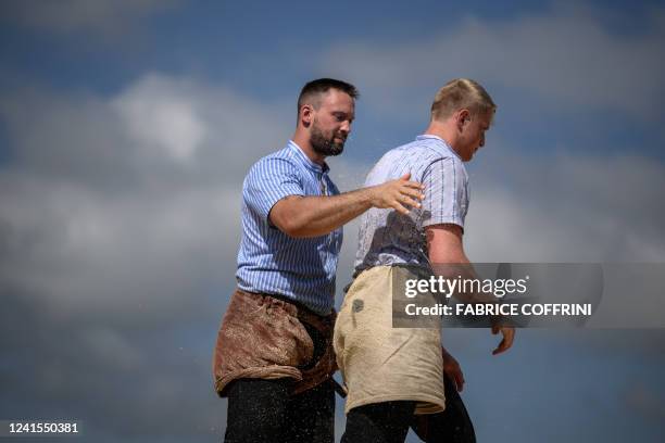 Wrestler Kilian Wenger removes the sawdust from the back of opponent Michael Ledermann after winning the match during the Bernese Jura Swiss...