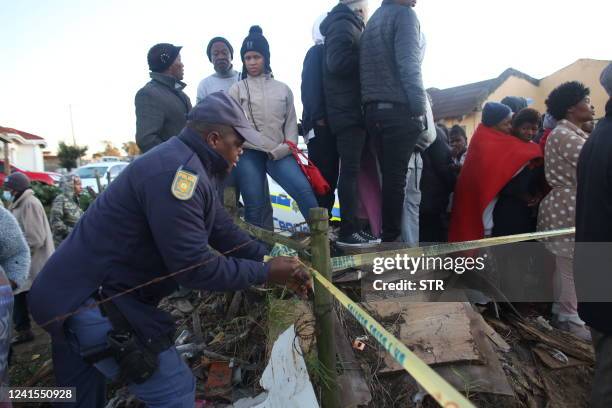 Police use tape to block off an area around a township pub in South Africa's southern city of East London on June 26 after 20 teenagers died. - At...