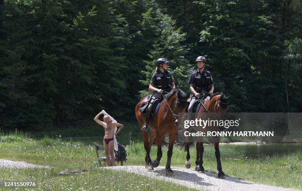 Mounted police ride past a swimmer towelling himself after taking a bath in lake Ferchensee near Mittenwald, southern Germany, where is taking place...