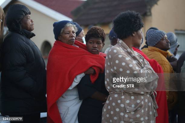 Members of the community and family wait for news outside a township pub in South Africa's southern city of East London on June 26 after 20 teenagers...