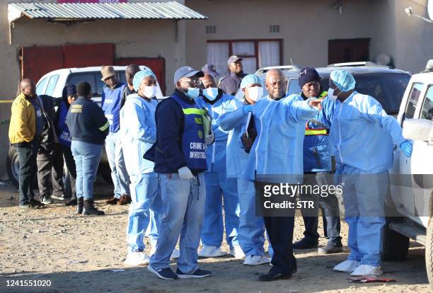 Police and investigators put on protective clothing before going into a township pub in South Africa's southern city of East London on June 26 after...