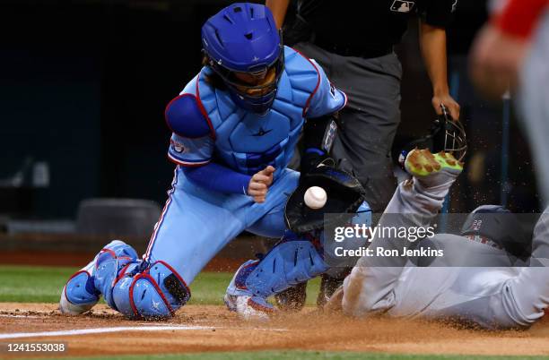 Juan Soto of the Washington Nationals slides head first into home plate to score a run as Jonah Heim of the Texas Rangers takes the throw during the...