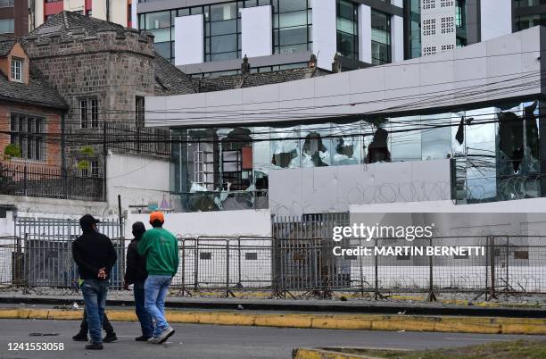 People walk by the vandalized comptroller's office near the National Assembly building in Quito on June 26 in the framework of indigenous-led...