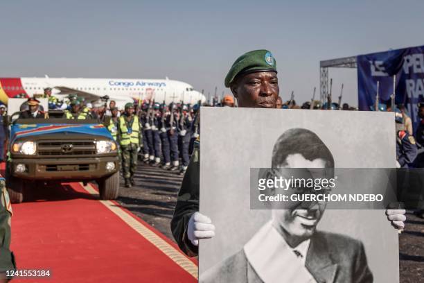 Portrait of slain Congolese independence leader Patrice Lumumba is carried as his remains leave for Shilatembo where the leader was killed along with...