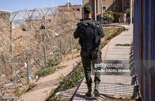 Picture taken on June 26 shows a member of the Moroccan security forces on the border fence separating Morocco from Spain's North African Melilla...