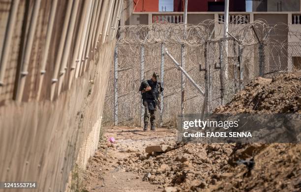 Picture taken on June 26 shows a member of the Moroccan security forces on the border fence separating Morocco from Spain's North African Melilla...