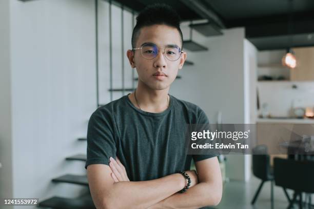 een aziatische chinese tienerjongen die camera bekijkt kruiste zijn wapen ernstig gezicht - chinese teenage boy stockfoto's en -beelden