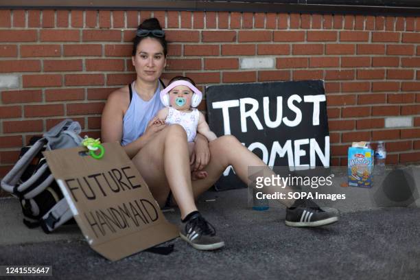 Rachel Humberger of Toledo holds her own 9 month old daughter Evelyn, and watches other children play during a protest against an anti-abortion...