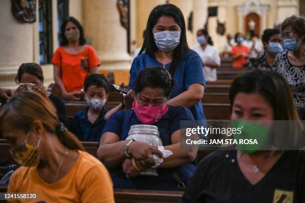 This photo taken on June 20, 2022 shows Gemma Enad holding an urn containing the ashes of an exhumed drug war victim, during a ceremony at the Sacred...