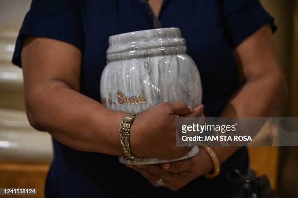 This photo taken on June 20, 2022 shows Gemma Enad holding an urn containing the ashes of an exhumed drug war victim, during a ceremony at the Sacred...