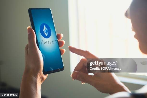 In this photo illustration, a woman holds a smartphone with the Ethereum logo displayed on the screen.