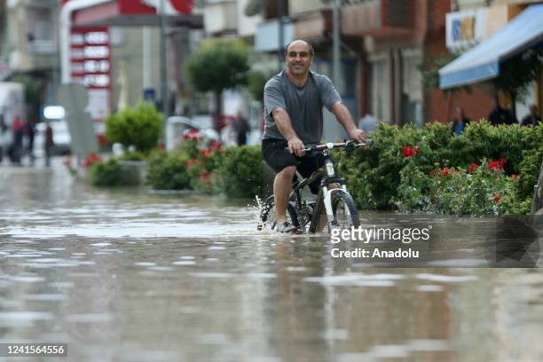 Man riding a bile wades through a flooded road after Avu Creek overflowed due to the heavy rains in Kozcagiz town of Bartin province, Turkiye on June...