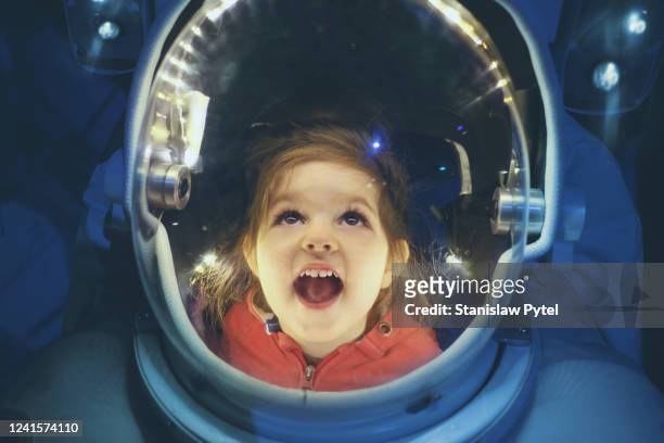small girl enjoying being inside of astronaut suit - scoperta foto e immagini stock