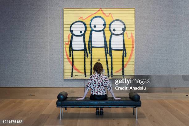 Staff member looks at a spray paint on steel garage door titled âChildren of Fireâ by STIK , estimate: Â£120,000 - Â£180,000 during a photo call for...