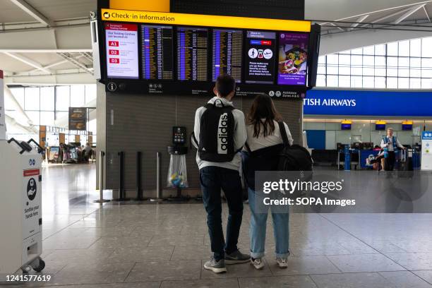Couple looks at an electronic flight information board at Terminal 5 of Londons Heathrow Airport. Hundreds of the flag carriers ground staff have...