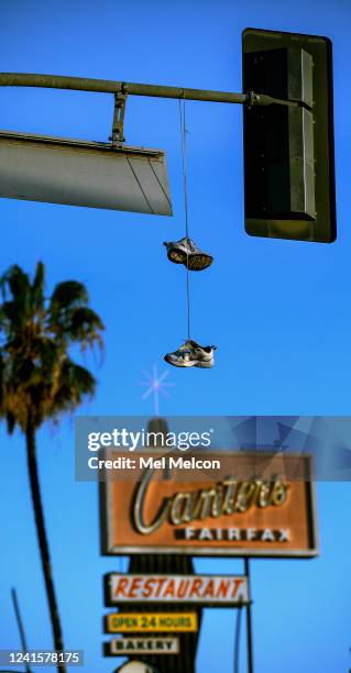 Pair of tennis shoes hang by their laces above Fairfax Ave. In between Melrose Ave. And Beverly Blvd., the real-life setting that inspired Amazons...