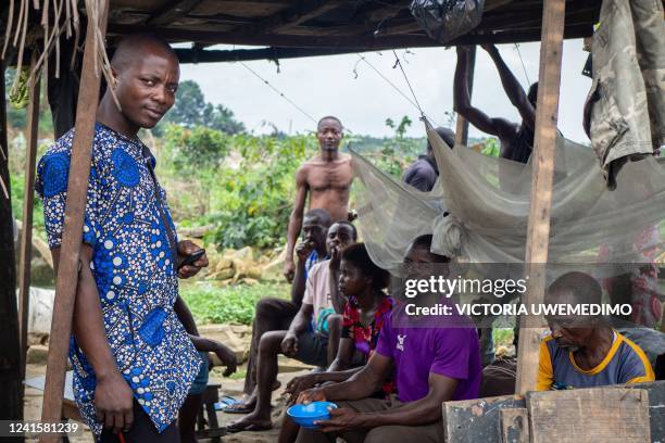 Several local residents cram themselves into this makeshift structure, to shelter from the downpours and mosquitoes brought about by the rainy...