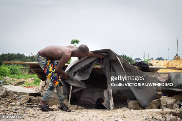 Favour stands next to a makeshift structure so that he can sleep there at night in Elechi, Port Harcourt, Nigeria, on March 10, 2022. - Port...