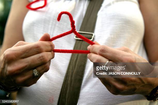 Protestor makes a coat hanger, a symbol of the reproductive rights movement, out of a pipe cleaner, while protesting for abortion rights in front of...