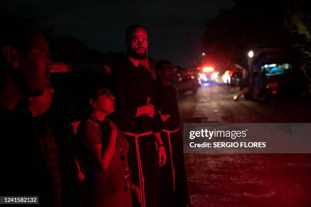 Local priests from the San Antonio Archdiocese stand near the scene where a tractor-trailer was discovered with migrants inside outside San Antonio,...