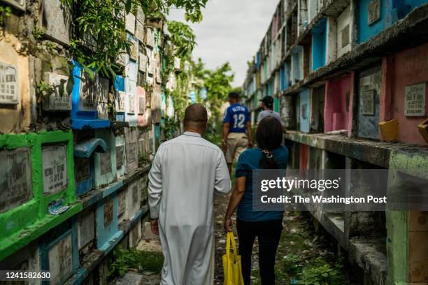 Catholic priest Father Flavie Villanueva walks with Janella Baran, widow of drug war victim Patricio Baran on June 10, 2022 at the Tala Cemetery in...