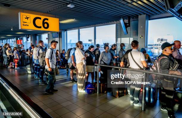 Travelers are seen waiting in departure halls to catch their flight from Schiphol airport. The airport now warns that there could be hours of queues...