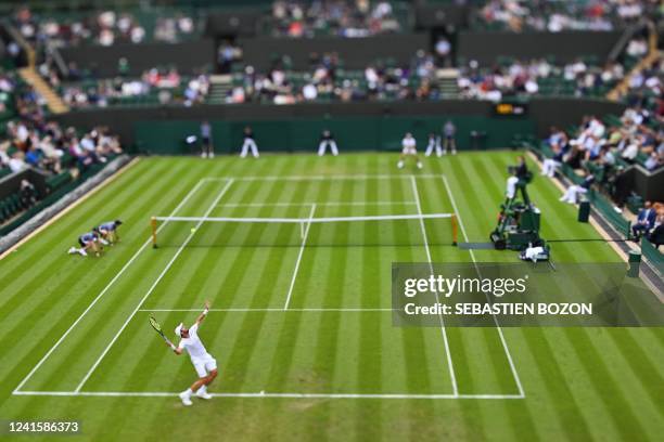 Player Steve Johnson serves the ball to Bulgaria's Grigor Dimitrov during their men's singles tennis match on the second day of the 2022 Wimbledon...