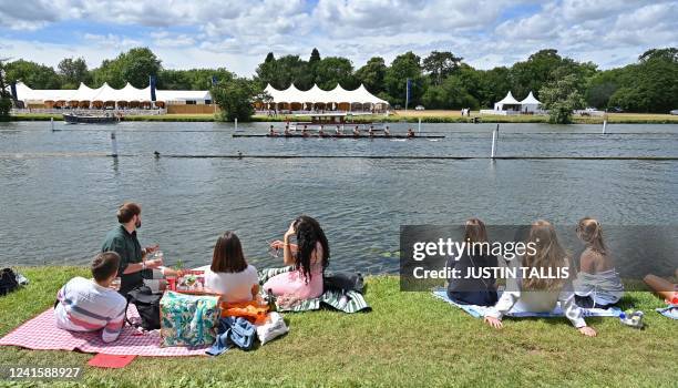 Spectators sit on the grass by the River Thames as they watch a race at the Henley Royal Regatta in Henley-on-Thames, west of London, on June 28,...
