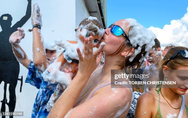 Festival goers are covered with foam as they party at the campsite of the Roskilde Festival, in Roskilde, Denmark, on June 28, 2022. - The music...