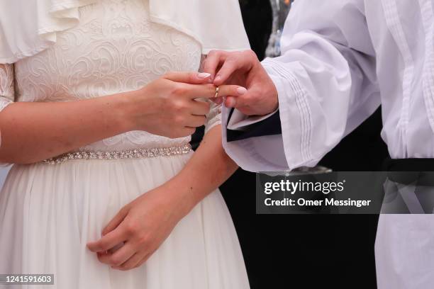 Groom Gabriel Grigoriev puts the wedding ring on the finger of Bride Elisheva Chaya under the Chuppah during a Jewish marriage ceremony held by...