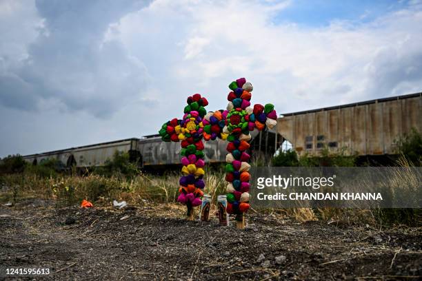 Cross and candles are kept at the spot where a tractor-trailer was discovered with migrants inside, outside San Antonio, Texas on June 28, 2022. US...
