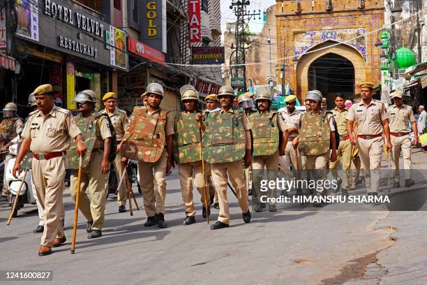 Policemen carry out a flag march through a street in Ajmer on June 29 following the alleged murder of a Hindu tailor by two Muslim men in Udaipur. -...