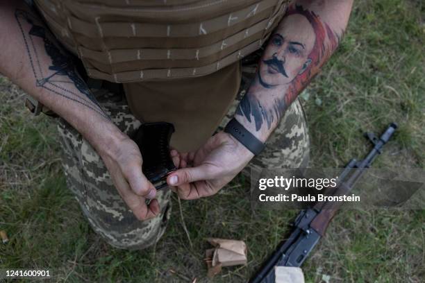 Man with a tattoo depicting the British criminal known as "Charles Bronson" reloads a weapon during Azov tactical training on June 28, 2022 in the...