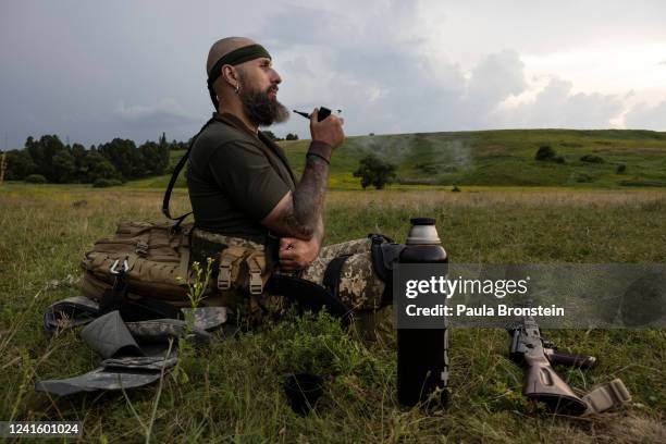 Arthur, an Azov Regiment member who joined a week ago, smokes a pipe while resting in a field during weapons training on June 28, 2022 in the Kharkiv...