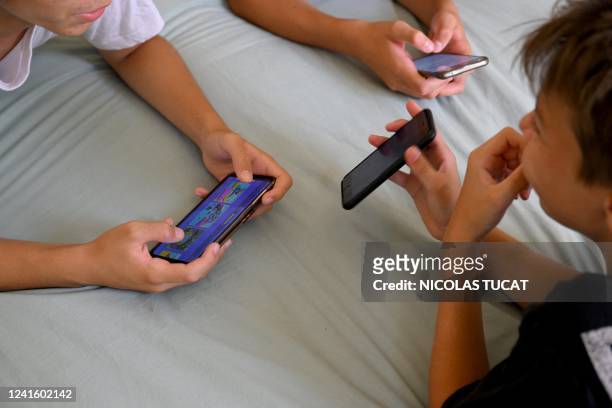 Teenagers hang on to their smartphones in Marseille, southern France, on June 27, 2022.