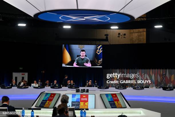 Ukraine's President Volodymyr Zelensky appears on a giant screen as he delivers a statement at the start of the first plenary session of the NATO...