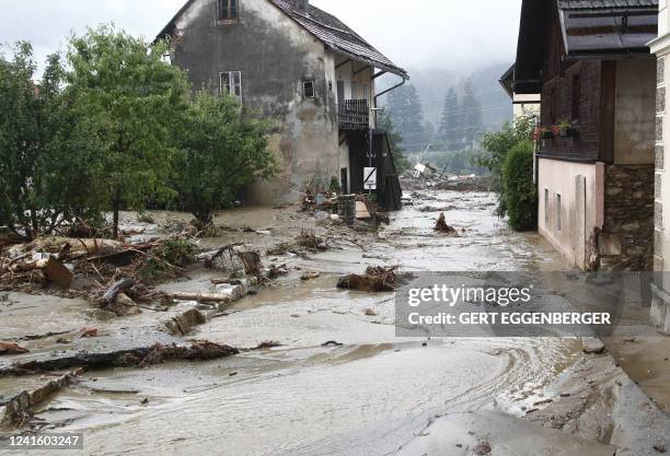 Debris and water stream downhill on a road among houses in Treffen, in the Villach-Land district of the Carinthia state, Austria, on June 29, 2022....