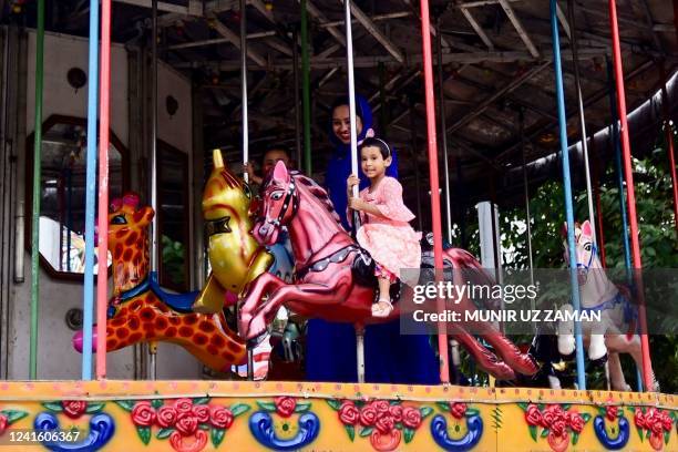 Children enjoy a merry-go round ride at an amusement park in Dhaka on June 29, 2022.