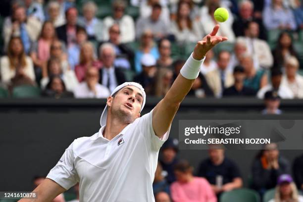 Player John Isner serves to Britain's Andy Murray during their men's singles tennis match on the third day of the 2022 Wimbledon Championships at The...