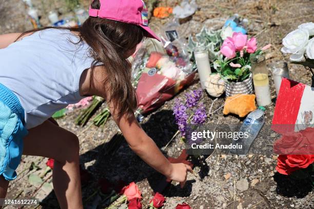 Girl leaves a cross and flowers where dozens of dead migrants found in a truck in San Antonio, Texas, United States on June 29, 2022.