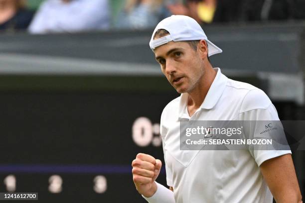 Player John Isner reacts as he competes against Britain's Andy Murray during their men's singles tennis match on the third day of the 2022 Wimbledon...