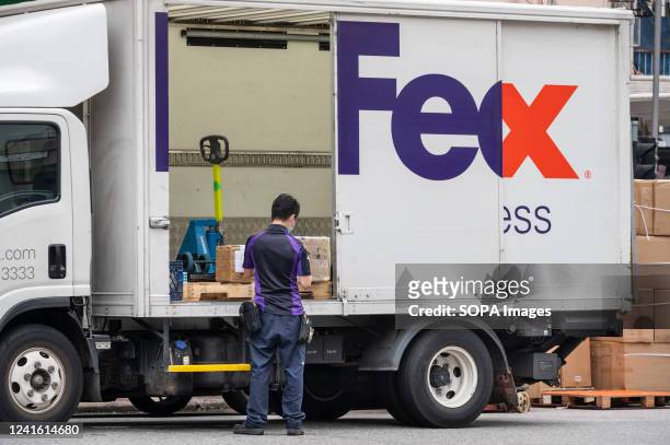 An American FedEx courier manages numerous order packages at the company delivery truck in Hong Kong.