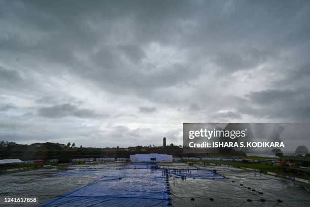 Sri Lanka's ground staff cover the ground as rain stops play during the second day of the first cricket Test match between Sri Lanka and Australia at...