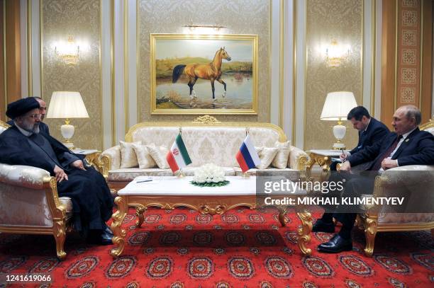 Russian President Vladimir Putin speaks with Iran's President Ebrahim Raisi during their meeting on the sidelines of the 6th Caspian Summit in...