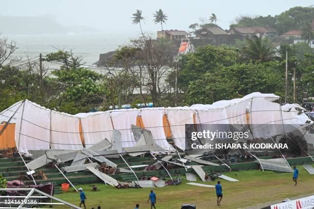 Ground staff stand next to a collapsed structure in a stand as rain and wind stopped play during the second day the first cricket Test match between...