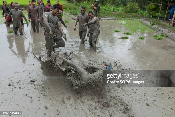 People play in mud water in a paddy field during the National paddy day celebration. Nepalese farmers celebrate National Paddy Day with various...