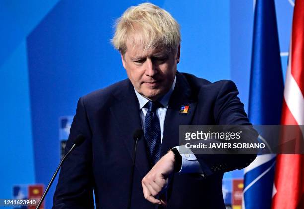 Britain's Prime Minister Boris Johnson looks at his watch as he addresses media representatives during a press conference at the NATO summit at the...