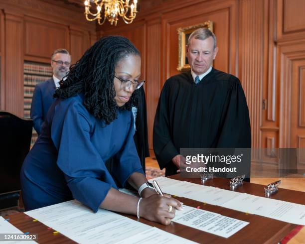 In this handout provided by the Supreme Court, Chief Justice John G. Roberts, Jr. Looks on as Justice Ketanji Brown Jackson signs the Oaths of Office...
